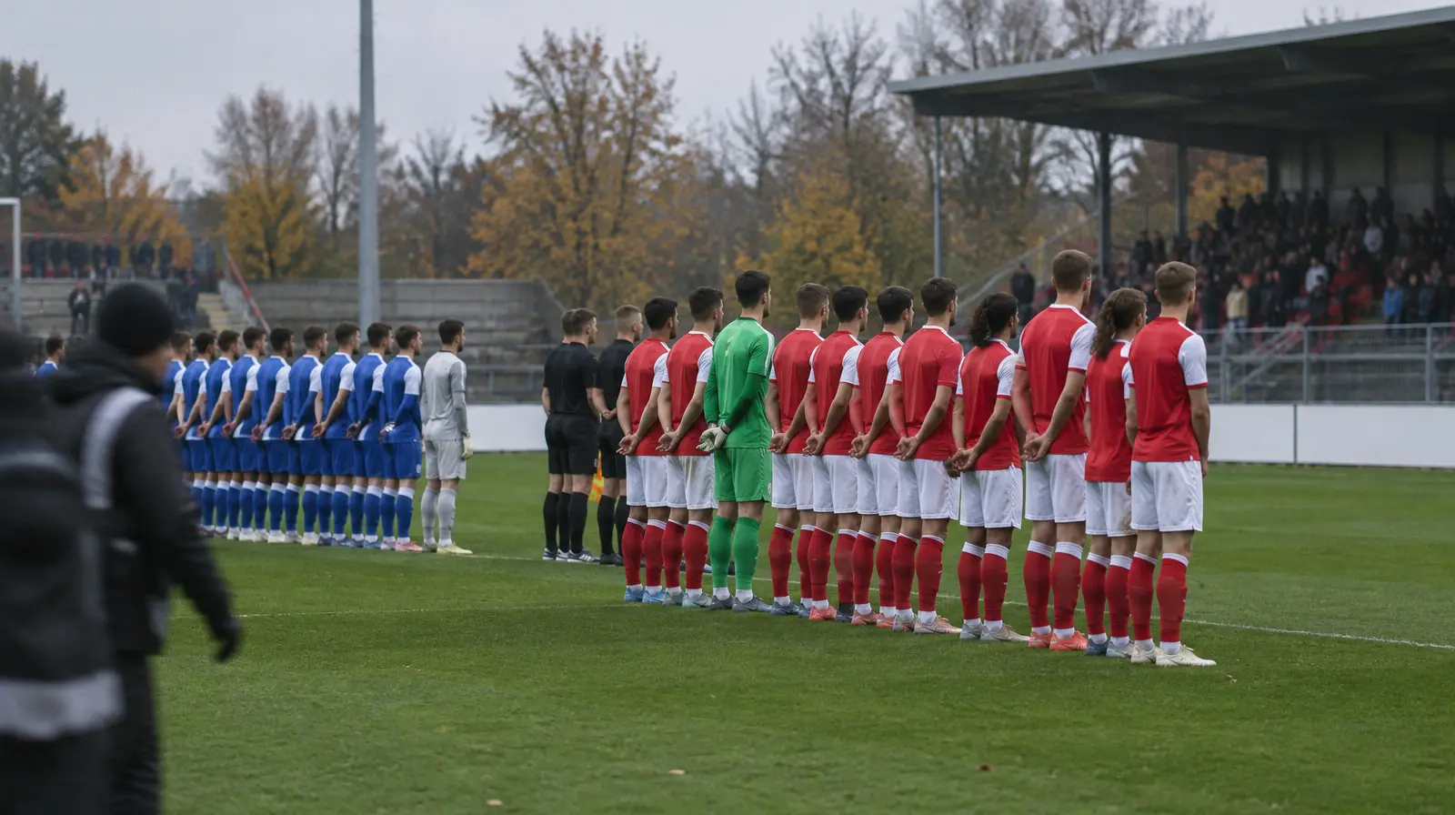 Spelare står uppställda inför avspark på en tysk fotbollsarena en höstdag